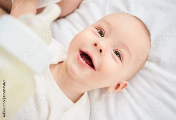 Obraz Cropped portrait of a smiling little toddler holding a bottle.