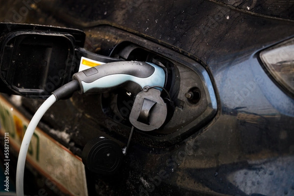 Obraz An electric vehicle being charged in a charging station