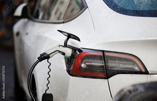 Obraz Electric Vehicle charging station system storing power on a white modern car. EV fuel for advanced hybrid car