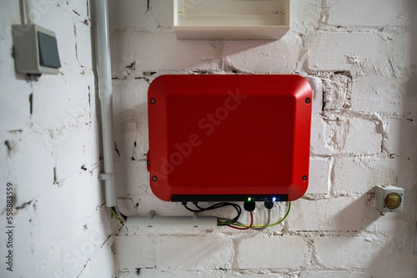 Obraz Red inverter of a photovoltaic system mounted on a white basement wall