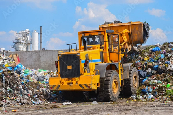 Fototapeta Wheel loader on landfill. Sorting rubbish by wheel loader 