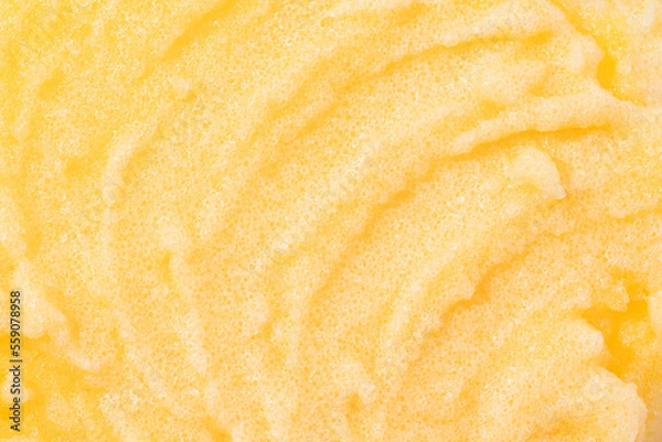Fototapeta Sugar or salt body scrub texture. Yellow scrub - skin care product with fruit extract as cosmetic background with copy space. Macro photo