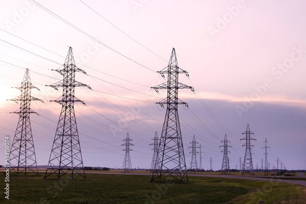 Fototapeta Network of power lines against the backdrop of the sunset sky. Power line towers.