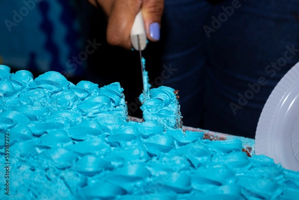 Obraz Cutting and separating piece of cake with blue icing.