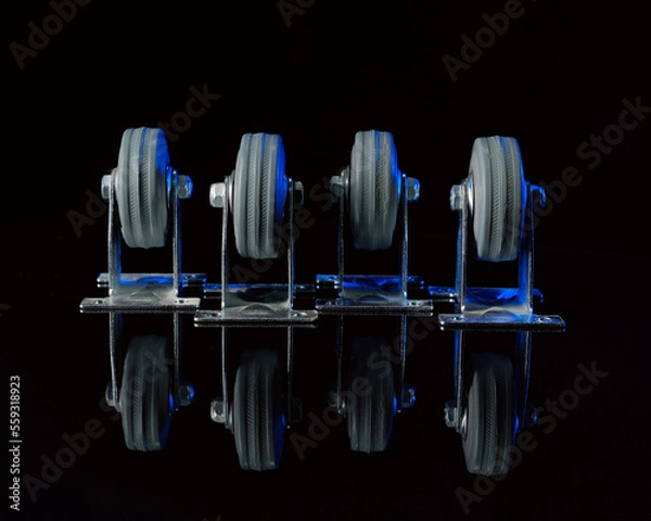 Obraz Rubber wheels in a metal frame on a black background with a reflection on the table.