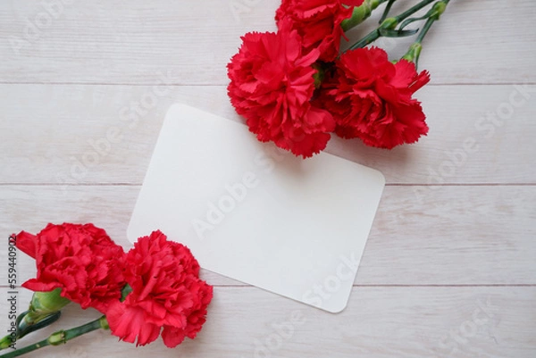 Fototapeta Red Carnation decoration with blank greeting card on wooden background. floral background for Mother's day, Women's day and Valentine's day. 