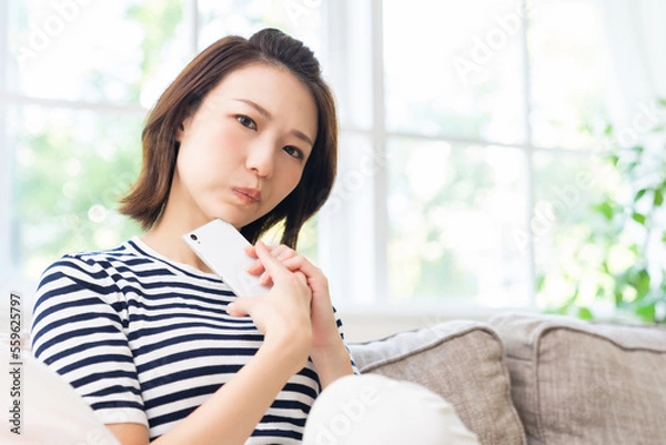 Fototapeta 部屋でスマホを見る女性　考える