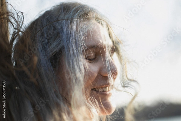 Fototapeta Close up tousled gray haired woman laughing with closed eyes portrait picture. Closeup side view photography with blurred background. High quality photo for ads, travel blog, magazine, article