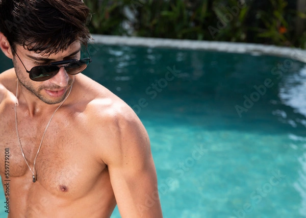Obraz man in swimming pool, handsome man in the pool, shirtless man looking to the side wearing sunglasses on a summer day, swimming pool in the background, copy space