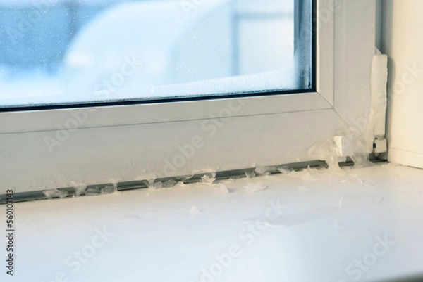 Fototapeta icicles on the window indoors. incorrect window installation, window adjustment, heating problems.