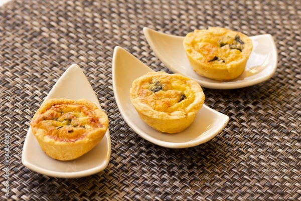 Fototapeta Baking Souffle. Three baked souffles in white small plates close-up. Gourmet fluffy potato suffle. Horizontal. Three portions top view.