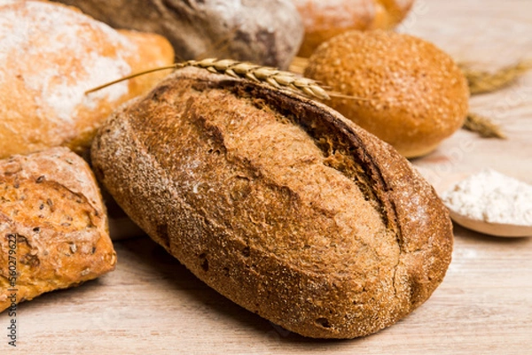 Fototapeta Homemade natural breads. Different kinds of fresh bread as background, perspective view with copy space