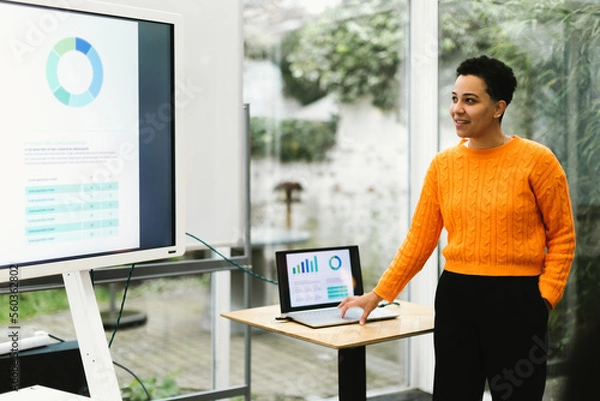 Fototapeta brazilian lady showing chart giving training using laptop and monitor tv in indoors classroom