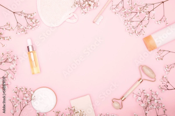 Fototapeta Frame from cosmetic products and hygiene items and dry flowers on a pink background. Beauty background. The concept of face and body care. copy space, flat lay.