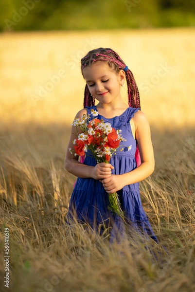 Fototapeta A six-year-old girl in a wheat field with a bouquet of flowers.