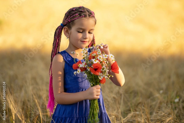 Fototapeta A six-year-old girl in a wheat field with a bouquet of flowers.