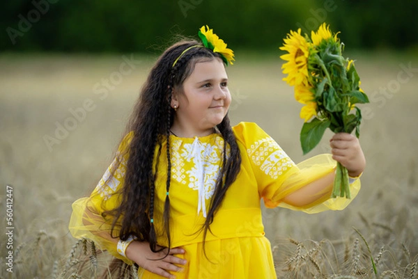 Fototapeta A girl in a wheat field with a bouquet of sunflowers.