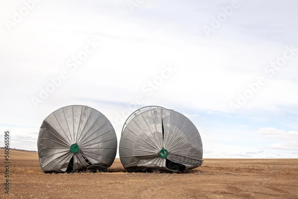 Fototapeta Front view of two steel grain bins toppled over from a windstorm in a rural autumn landscape