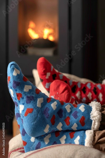 Fototapeta winter socks with hearts patterns in the background pellet stove lit, two pairs of feet boy and girl, couple inside warm and comfortable.