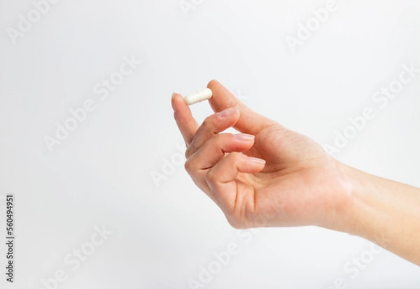Obraz Hand holding a tablet on a white background, supplementation and health, physical and mental health concept