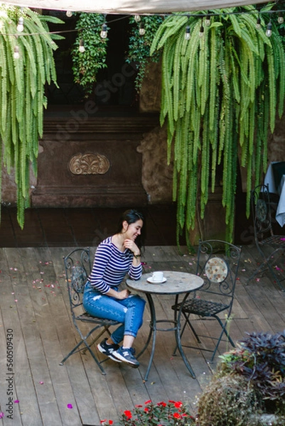 Fototapeta young woman drinking coffee and working at a table while having breakfast