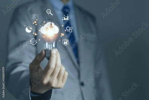 Fototapeta Businessman holding a light bulb showing a diagram of Cloud computing information technology icon.