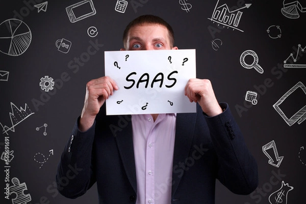 Fototapeta Business, Technology, Internet and network concept. Young businessman working on a virtual screen of the future and sees the inscription: SAAS