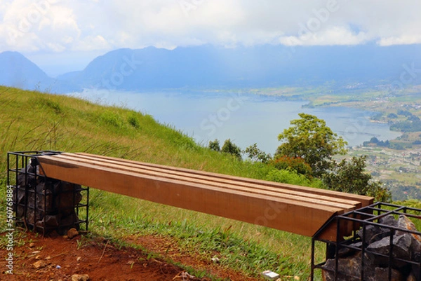 Fototapeta a unique wooden bench on the hill of Lawang Indonesia with views of Lake Maninjau below