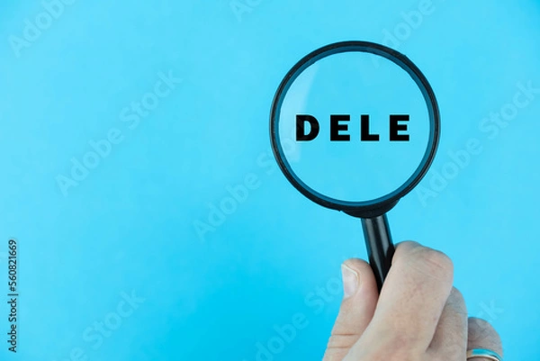 Fototapeta Focused on DELE exam. Word DELE (Diploma de Español como Lengua Extranjera) under magnifying glass. Spanish Language Proficiency Test. Test Preparation. E-learning.