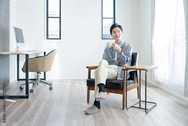 Obraz 家でコーヒーを飲んでリラックスする若い男性