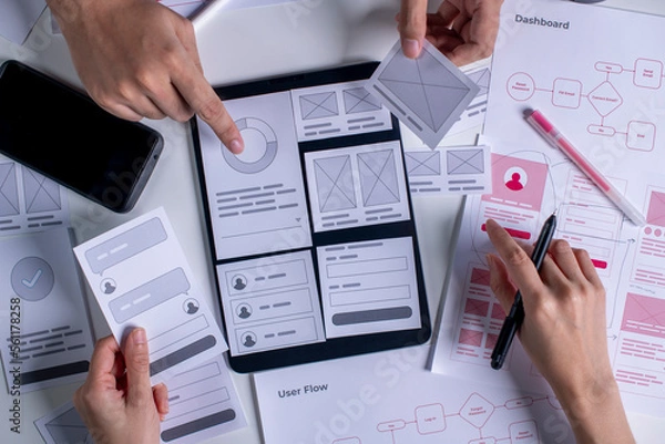 Obraz Close up ux developer and ui designer brainstorming about mobile app interface wireframe design on table.