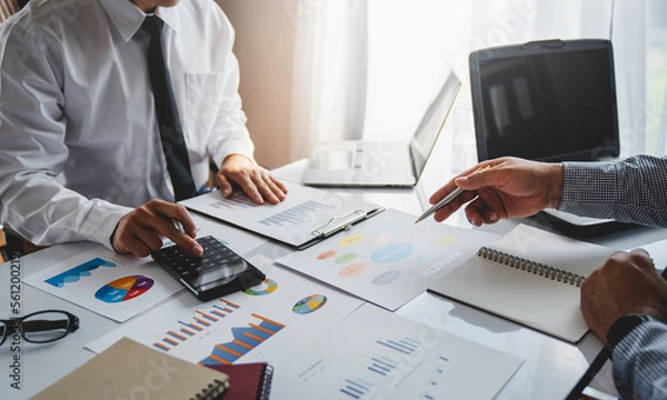 Fototapeta Two young Asian businessmen have a meeting on a real estate project. Planning and calculating, clarifying the information in the graph analyzing business finance charts, and accounting concepts.