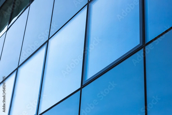 Fototapeta The blue sky is reflected in the windows of a modern office building. Architecture and exterior of contemporary houses