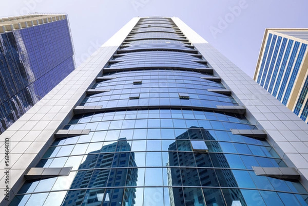 Fototapeta Symmetrical view of a modern skyscraper with a glass facade in Dubai, as seen from street level