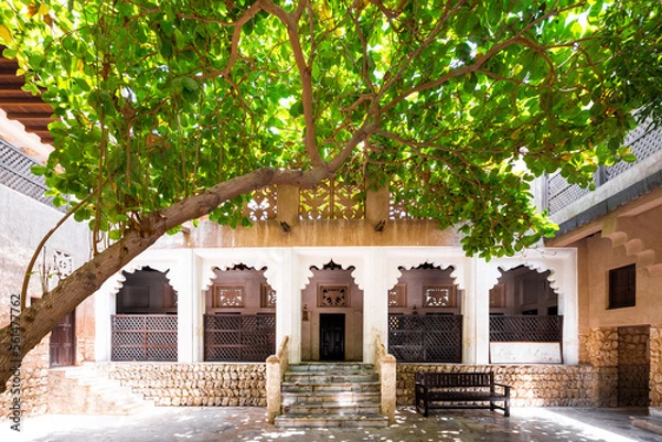 Fototapeta Ancient traditional house in old Dubai, with a porch lined with marble columns providing shade and an oak tree in the foreground