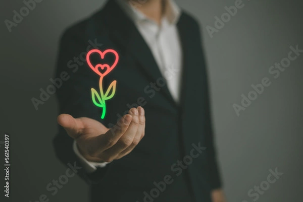 Obraz Man handing heart shape on hand a red heart There are green flower stalks.