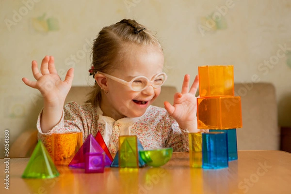 Fototapeta A girl with Down's syndrome lays out geometric shapes