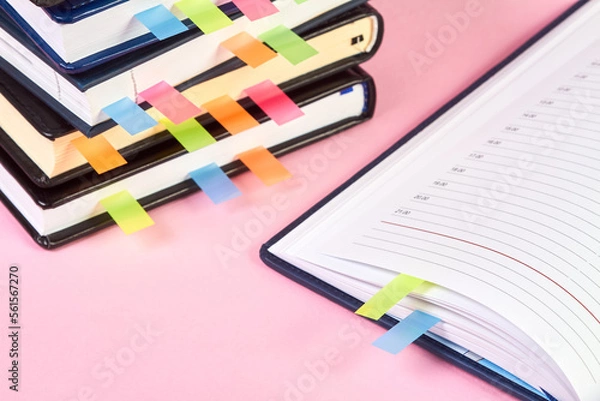 Obraz Close-up of an open notepad with colorful sticky page markers on background of a stack of office notepads