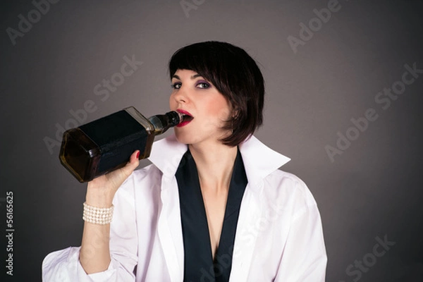 Obraz beautiful woman in a man's shirt is drinking from a bottle