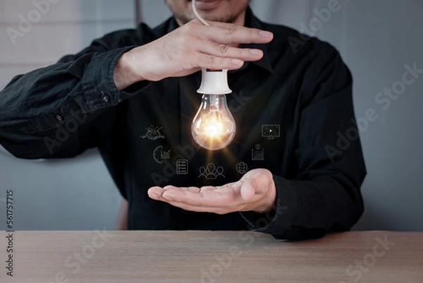 Fototapeta Businessman touching a bright light bulb. Concept of Ideas for presenting new ideas Great inspiration and innovation new beginning.
