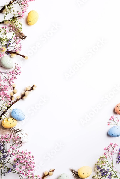 Fototapeta Border with Easter composition with spring flowers and colorful quail eggs over white background. Springtime and Easter holiday concept with copy space. Top view