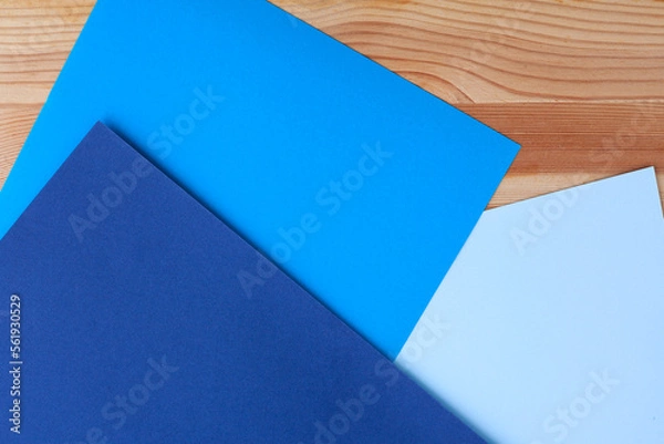 Fototapeta Sheets of colored cardboard on a wooden table. Different blue shades, paper empty background. Creative Concept. Copy space.