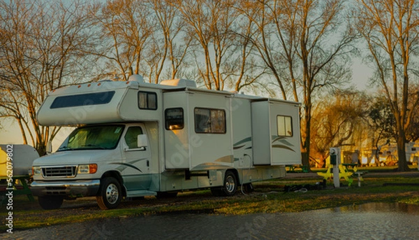 Fototapeta Rv class C motorhome with slides out parked camping next to water early morning light