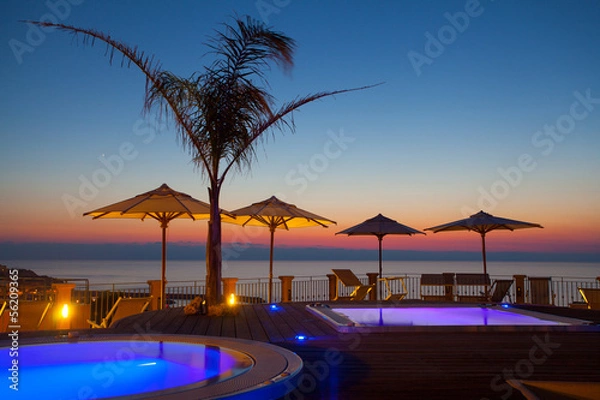 Fototapeta Summer time: beautiful dawn at pool area with palm and parasols,