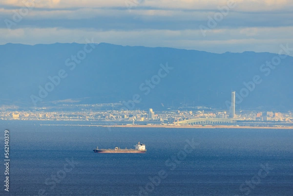 Fototapeta Cargo Ship Sails to Port in Osaka Bay by Rinku Gate Tower on Sunny Day