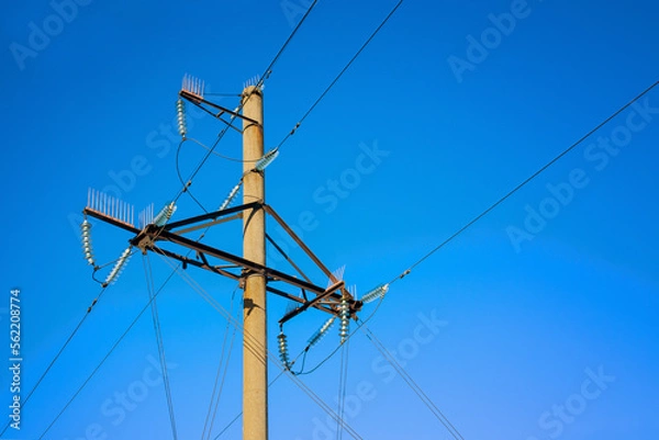 Fototapeta Overhead power line support on the blue sky background.