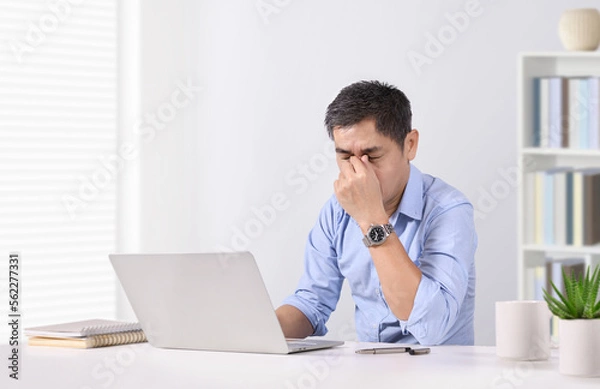 Obraz Overworked businessman eye strain after long laptop usage.