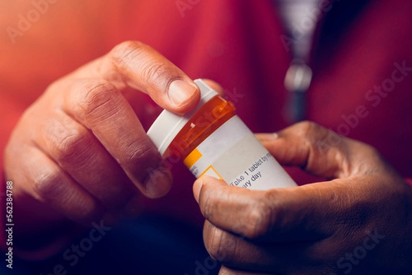 Fototapeta close up of man at home sitting down handling prescription pill bottle