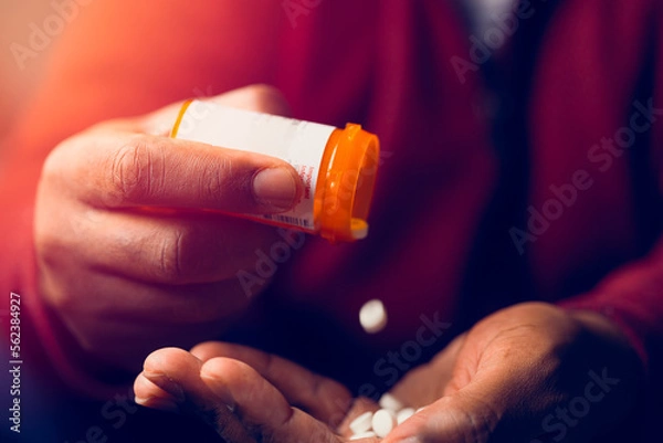 Fototapeta close up of man at home sitting down handling prescription pill bottle