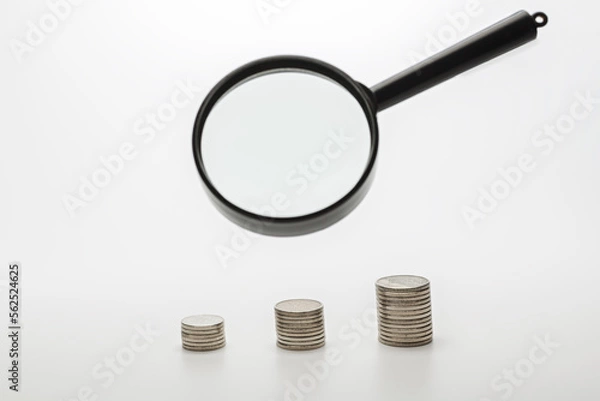 Obraz Magnifying glass with coins on gray background. Concept of banking, credit or search money.